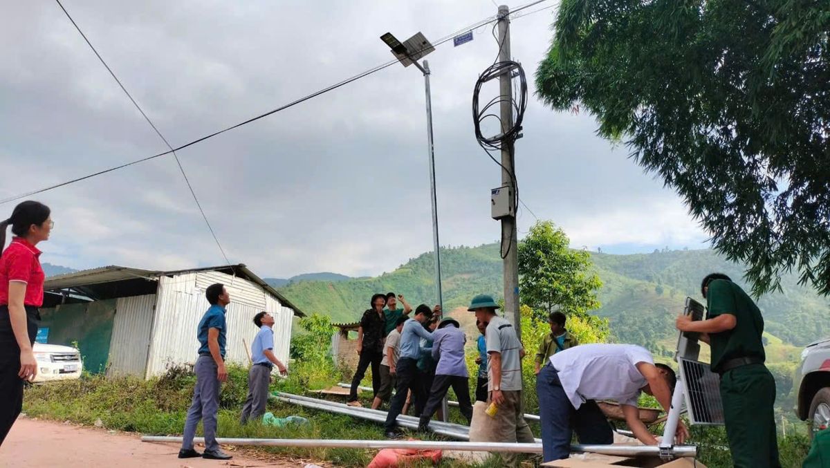 Người dân và đội thi công lắp đèn đường